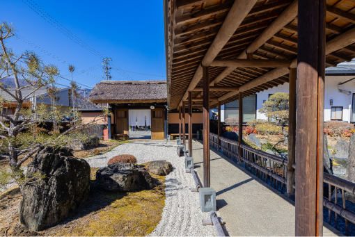 お宿 山翠の玄関の写真です。砂利の庭と、屋根付きの廊下が見えます。