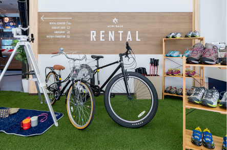 レンタルの文字と自転車の写真です。店内には自転車2台と靴が並んでいます。左には望遠鏡とござが見えます。
