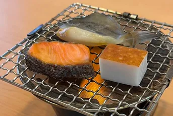 炭火焼きの網の上で焼かれる三種の魚