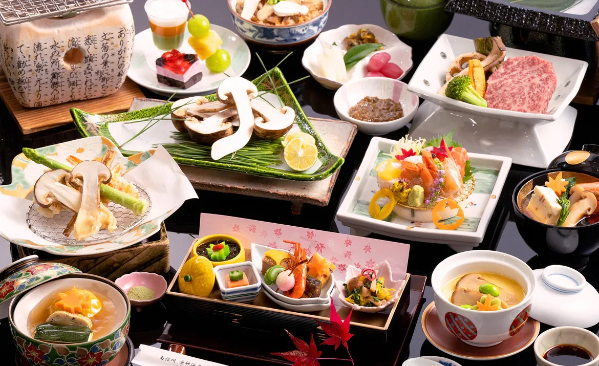 松茸や和牛、刺身などを盛り込んだ華やかな秋の会席料理。焼き物、天ぷら、小鉢、茶碗蒸し、デザートが上品に並ぶ。