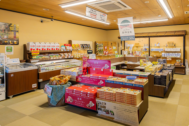 地元のお土産が並ぶ、明るく開放的なお土産処。木製の棚に商品が並び、温かみのある空間を演出します。